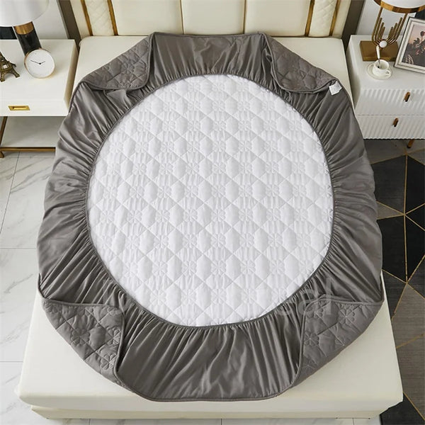 A gray durable waterproof mattress protector with a quilted white top placed on a white surface.