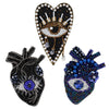 A collection of sparkling beaded rhinestone patches featuring an eye design, including a gold-toned eye and a blue/purple iri