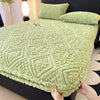 A light green textured plush mattress cover is shown on a bed, with hands holding the edge.