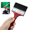 A red paint brush with a black bristles and plastic handle is shown being held by a hand.