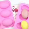 A pink silicone mold tray containing several pink and yellow oval-shaped silicone molds for crafts and soap.