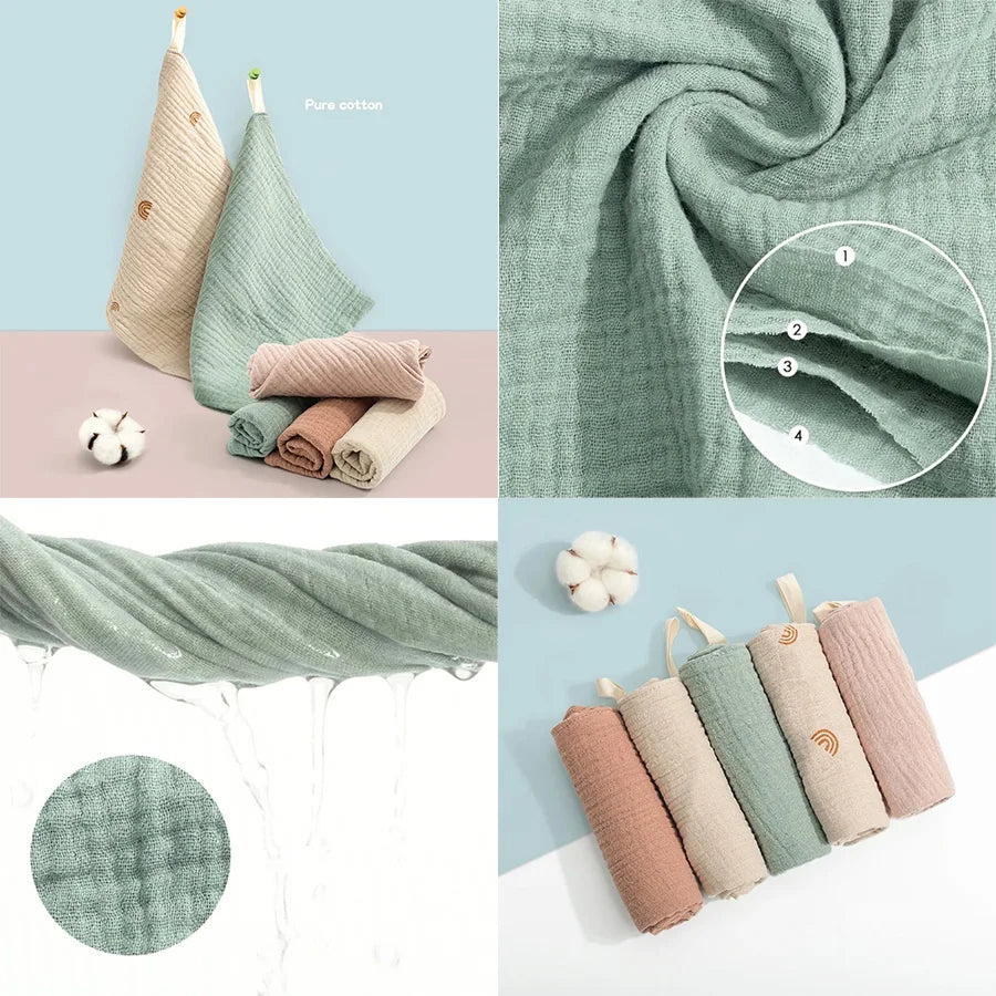 A collection of soft cotton gauze burp cloths in various shades of sage green and pink, including a folded cloth and a rolled