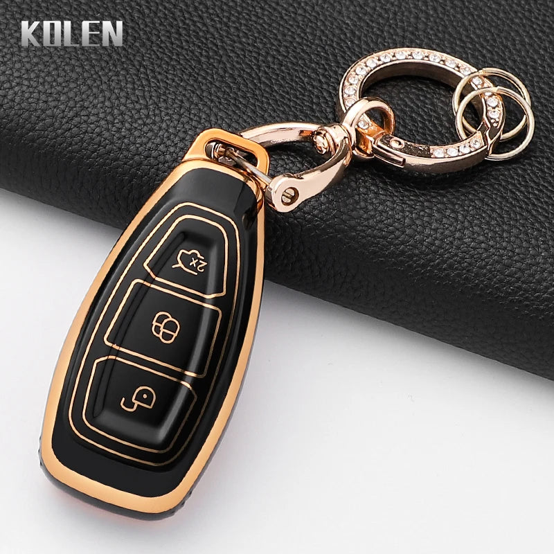 A gold-toned silicone car key fob cover with a black body and decorative elements, attached to a silver chain.