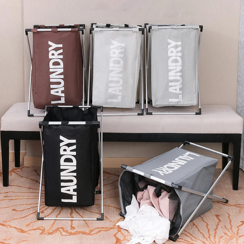 Three silver racks hold three large fabric laundry baskets in brown, white, and black.