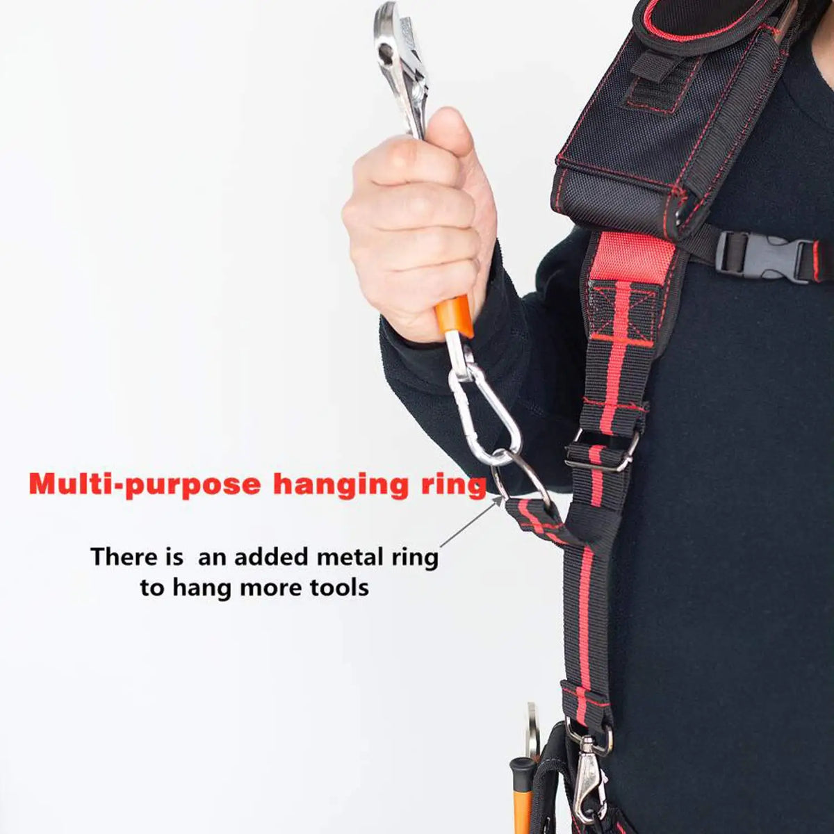 A hand is holding a multi-purpose hanging ring attached to a tool belt strap.