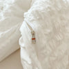 Close-up of a white lightweight seersucker duvet cover set showing a zipper detail.