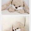 A light brown, long-eared angry rabbit plush toy is shown lying down on a white surface.