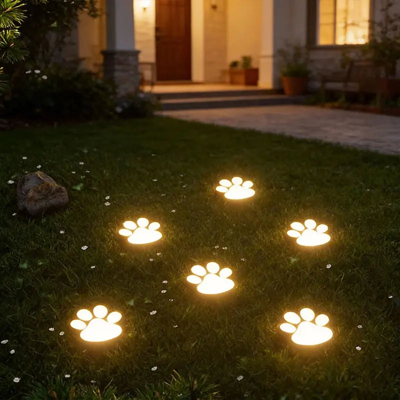 Four glowing dog paw lights arranged in a diamond pattern on a green lawn leading to a doorway.