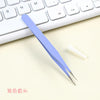 A pair of light blue precision craft tweezers with straight and curved tips resting on a white keyboard.