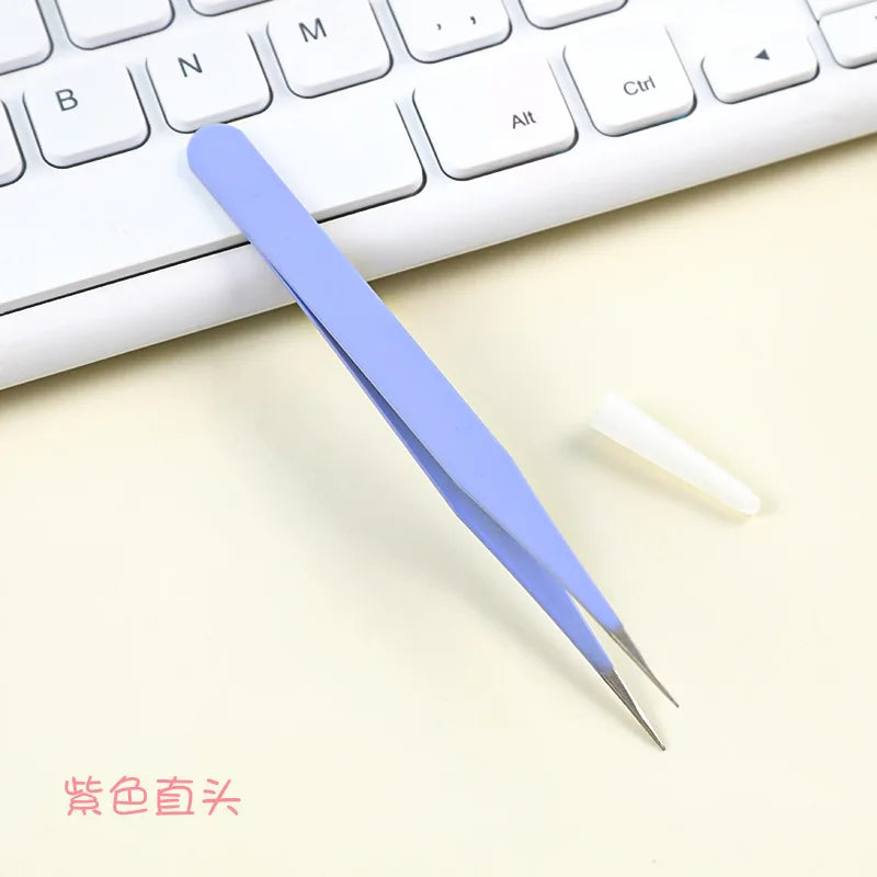A pair of light blue precision craft tweezers with straight and curved tips resting on a white keyboard.