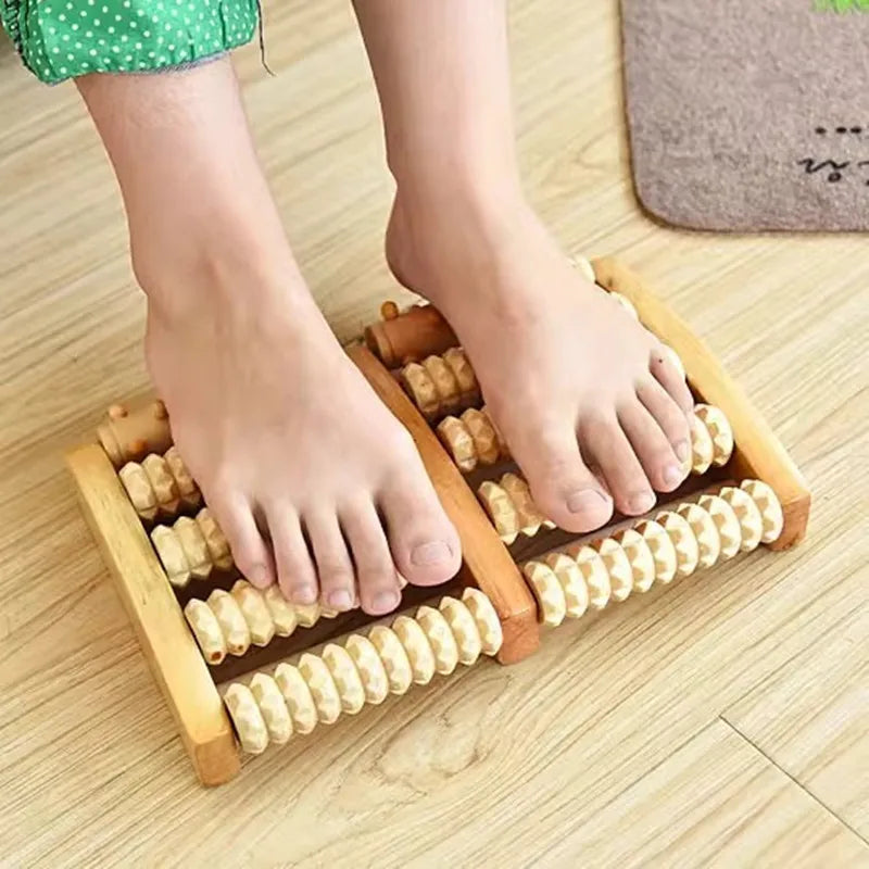 A pair of feet resting on a wooden foot massage roller used for reflexology and tension relief.