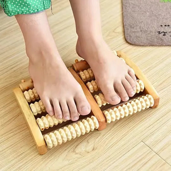 A pair of feet resting on a wooden foot massage roller used for reflexology and tension relief.