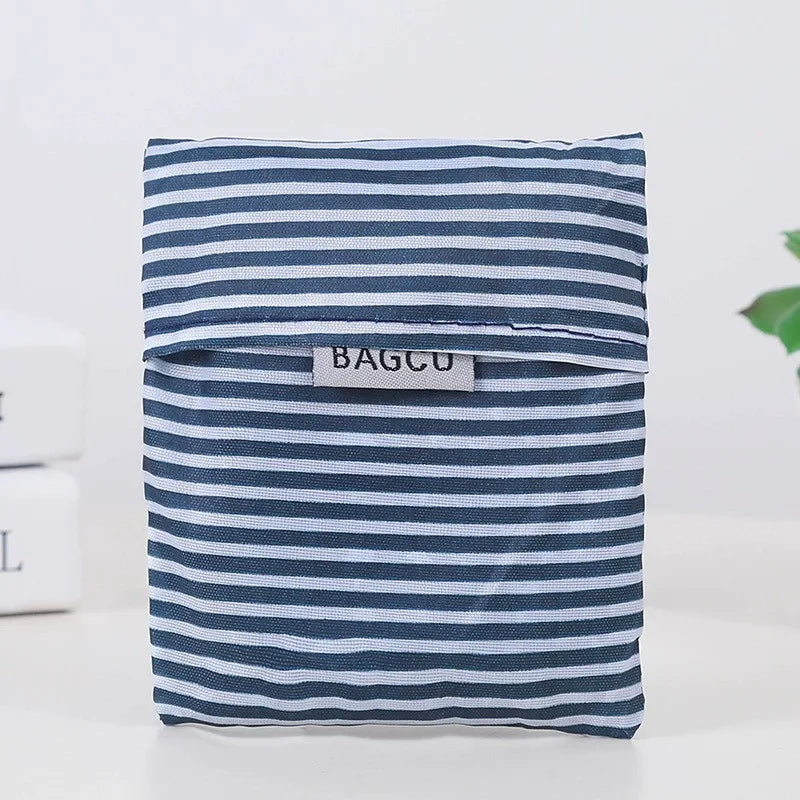 A navy and white striped fabric shopping bag with a rectangular tag labeled BAGCU