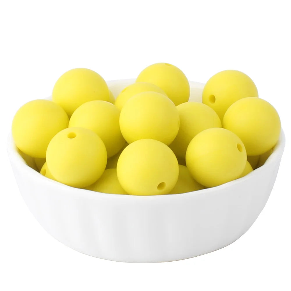 A white bowl filled with numerous yellow silicone beads for jewelry making