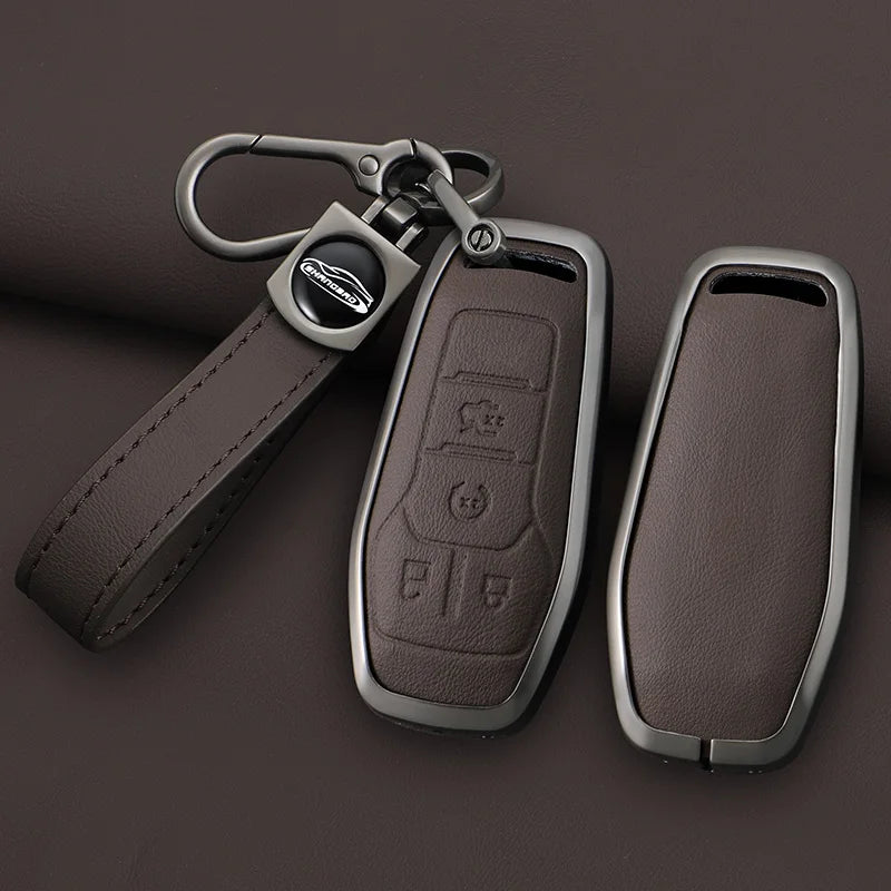 A dark brown leather key case cover with a metal fob and chain attached, shown against a dark background.