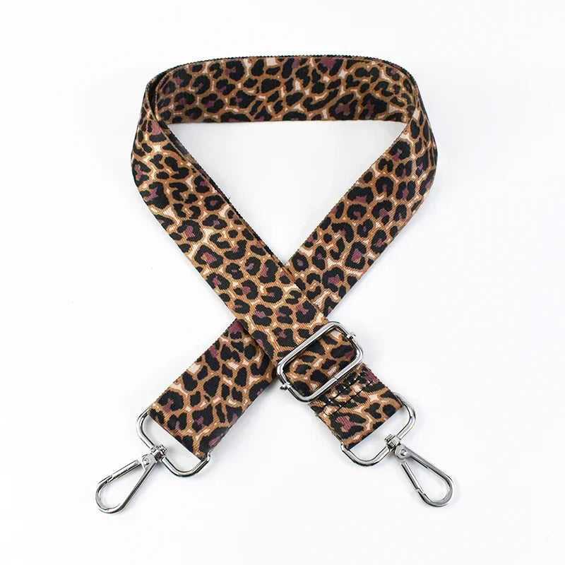 A brown leopard print wide adjustable crossbody bag strap with silver hardware.
