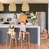 A family is gathered around a kitchen island with a refrigerator, featuring child safety locks.