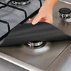 A hand places a black reusable gas stove burner protector onto a stovetop grate.