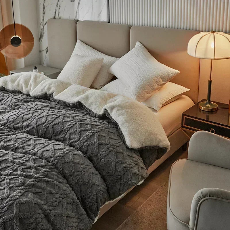 A luxurious gray velvet duvet cover and blanket with white pillows on a bed in a bright room.