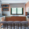 A row of four upholstered bar stools with gray fabric slipcovers are positioned in front of a modern kitchen window.