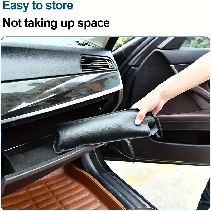 A hand is opening a black foldable car windshield sunshade umbrella inside a car.