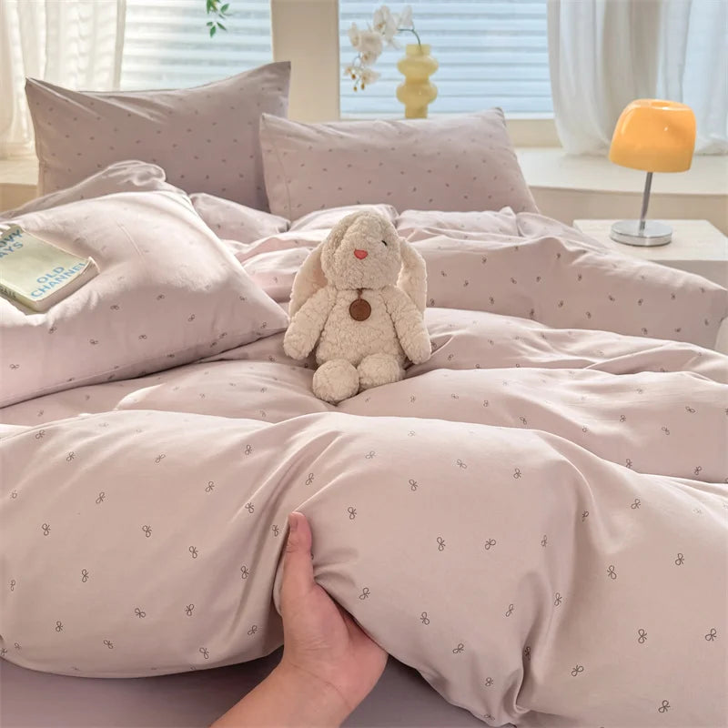 A light pink duvet cover set featuring a cute, fluffy rabbit plush toy on the bed.