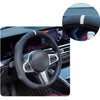 Close-up view of a black steering wheel with silver accents and a white accent stripe on the rim.