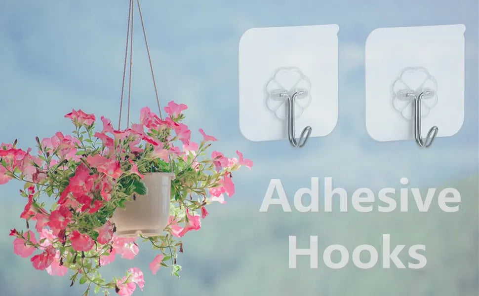 White adhesive hooks hanging on a wall next to a pink flowering plant