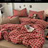 A red and black plaid duvet cover set with matching pillows and a stuffed animal on a bed.