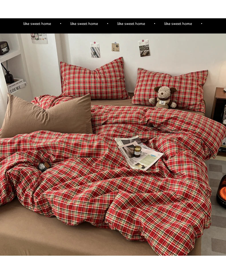 A red and black plaid duvet cover set with matching pillows and a stuffed animal on a bed.