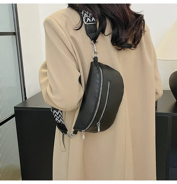A woman is holding a black multi-pocket PU leather waist bag with an adjustable strap against a light beige coat.
