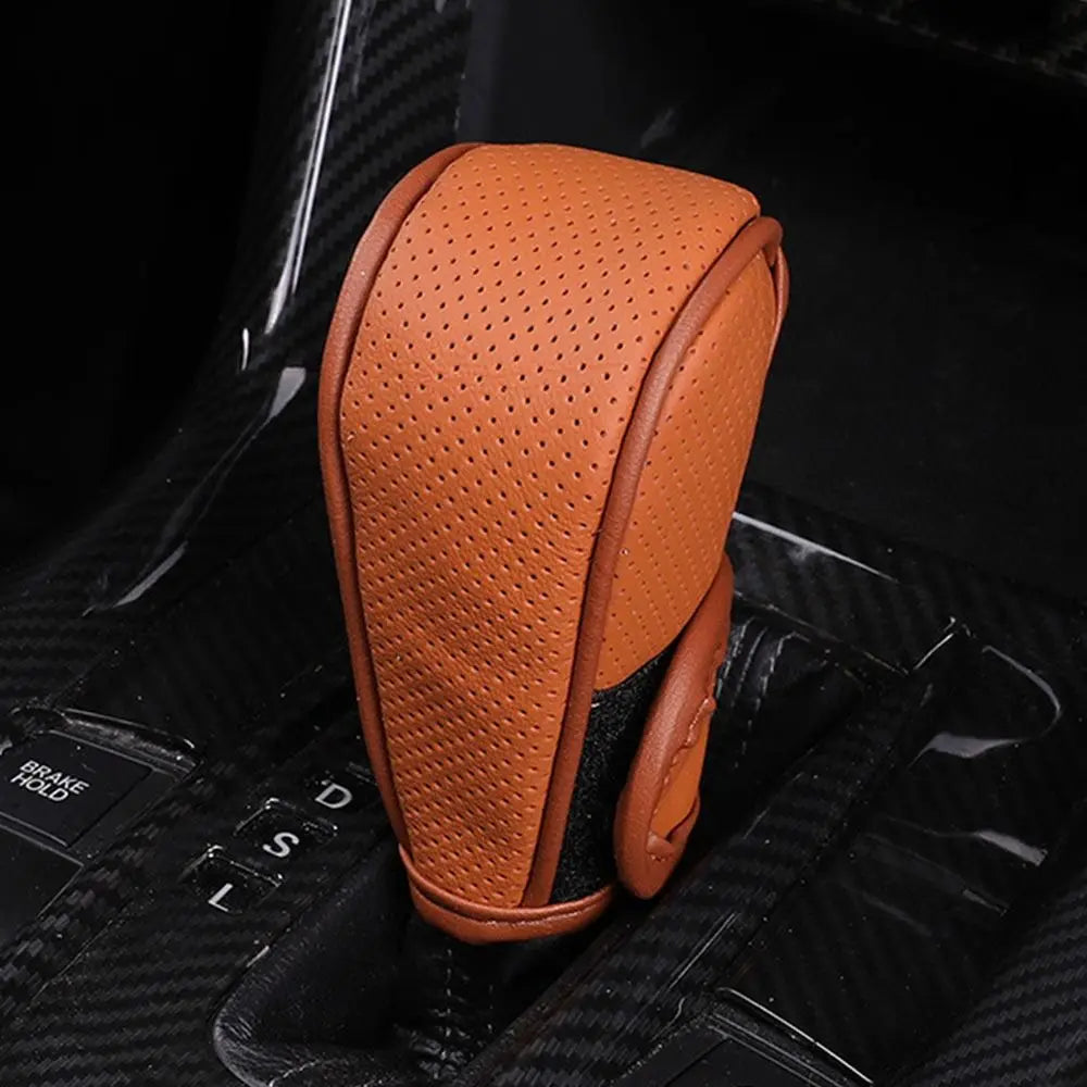 An orange leather gear shift knob cover with a perforated texture is shown against a black background.