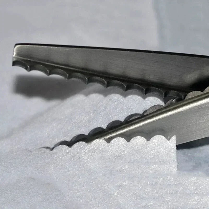 Close-up of professional scalloped pinking shears with serrated blades resting on white fabric.