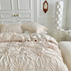 A light pink luxury duvet cover set featuring a 3D twist floral pinch-pleated pattern on a bed.