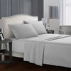 A white bed with soft gray bedding, including a fitted sheet, flat sheet, and pillows, in a modern bedroom setting.