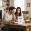 A couple smiling while looking at a personalized fill-in-the-blank love book for an anniversary keepsake journal.
