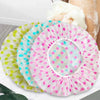 A pink polka-dotted disposable waterproof shower cap is shown next to other similar caps.