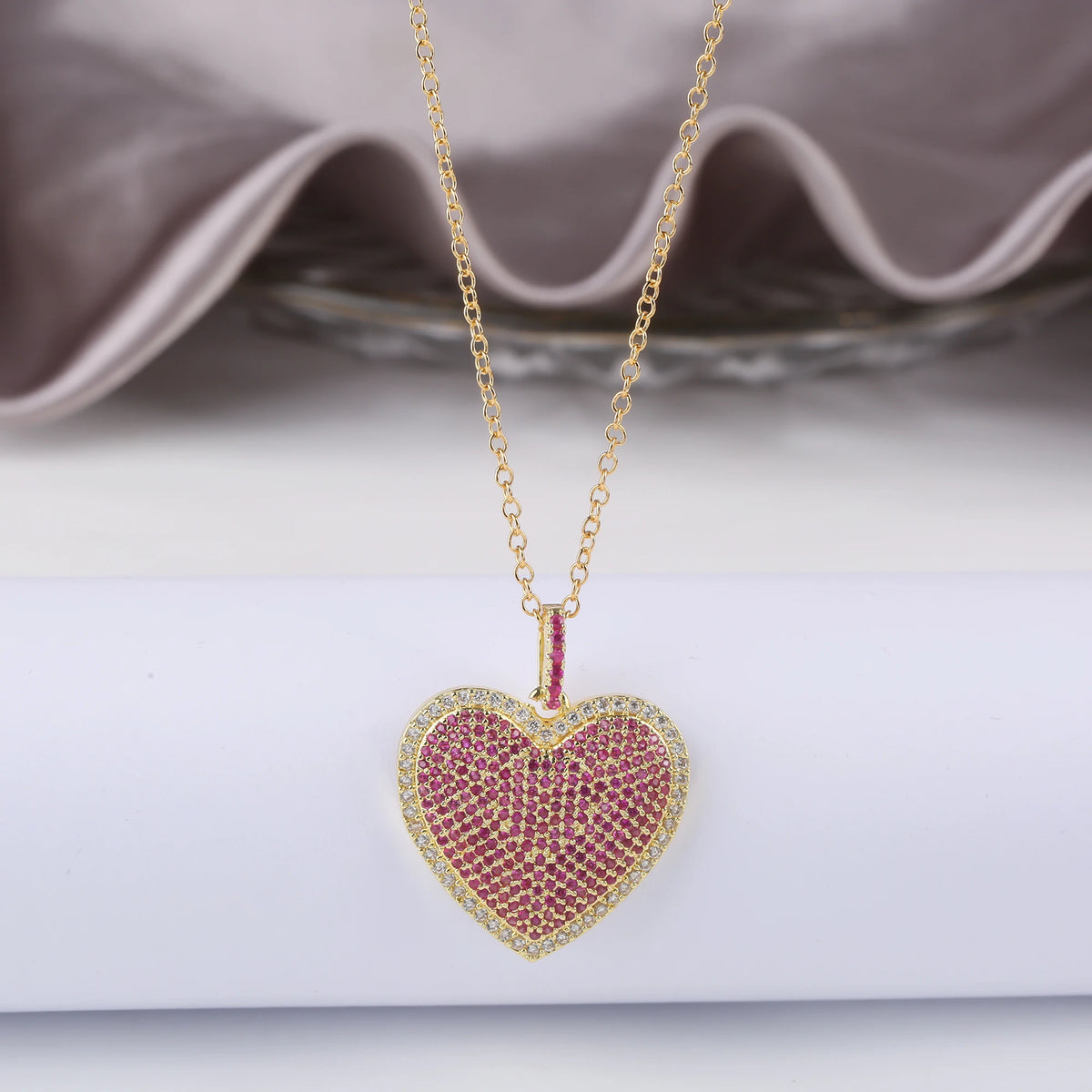 Gold chain necklace with a heart-shaped pendant encrusted with pink and yellow cubic zirconia stones