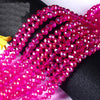 A close-up of bright pink faceted crystal glass spacer beads arranged in strands.