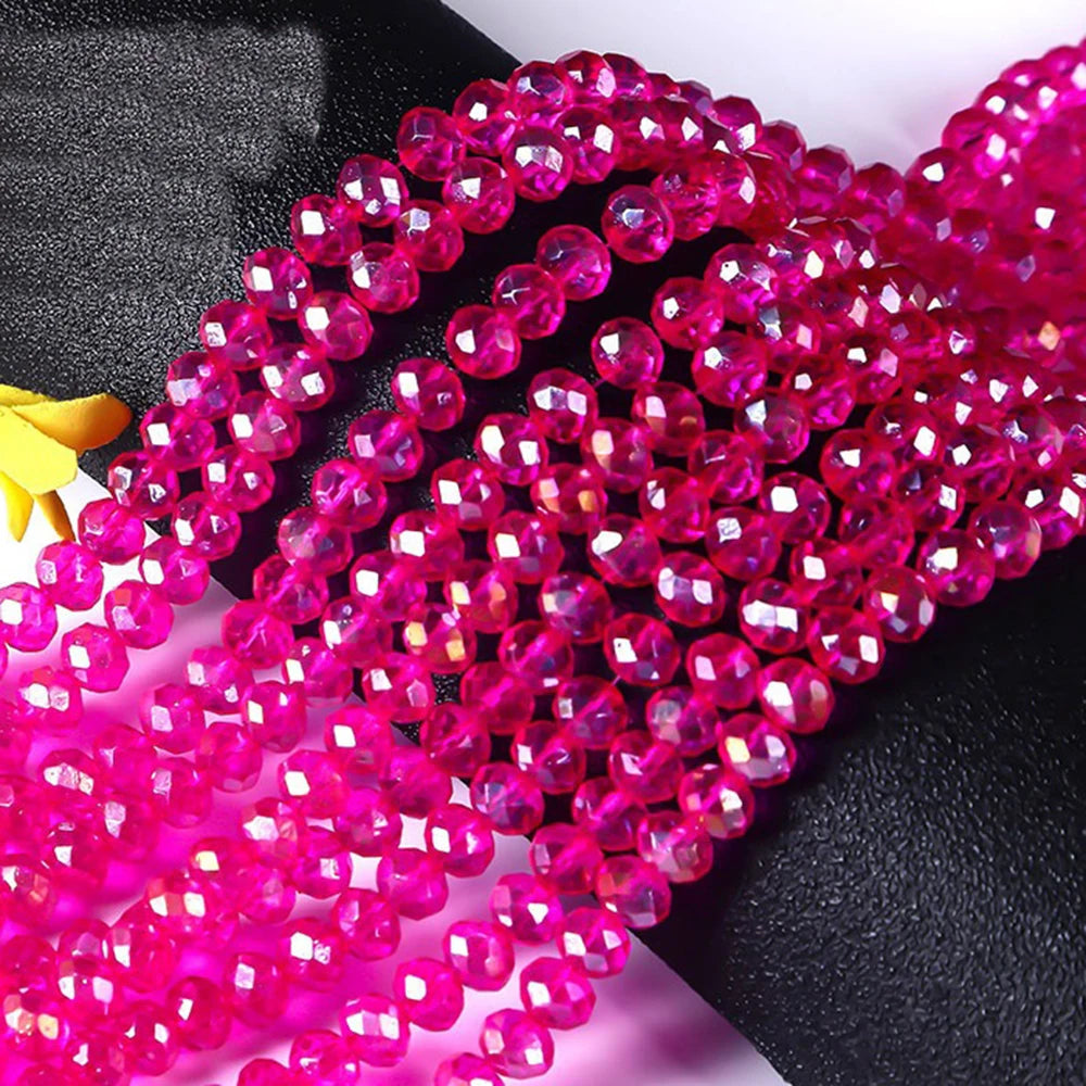 A close-up of bright pink faceted crystal glass spacer beads arranged in strands.