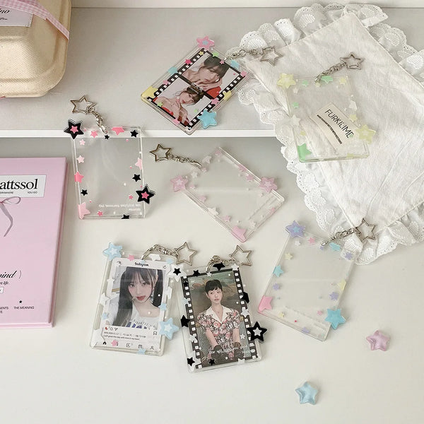 Transparent acrylic photocard holder with star pendant keychain displayed on a white surface.