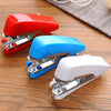 Three portable handheld sewing machines in red, blue, and white lying on a wooden surface.