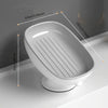 White leaf-shaped suction cup soap dish with drainage grooves shown on a bathroom counter.