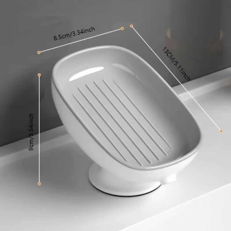 White leaf-shaped suction cup soap dish with drainage grooves shown on a bathroom counter.