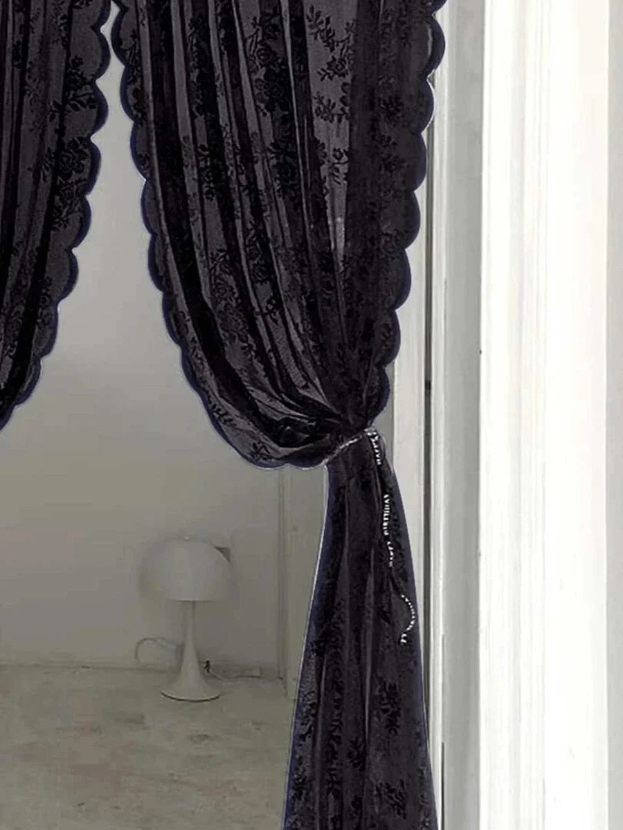 Un rideau transparent violet foncé avec broderie florale drapé dans un cadre de fenêtre.