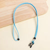 A bright blue adjustable lanyard for glasses is displayed on a light wooden surface.