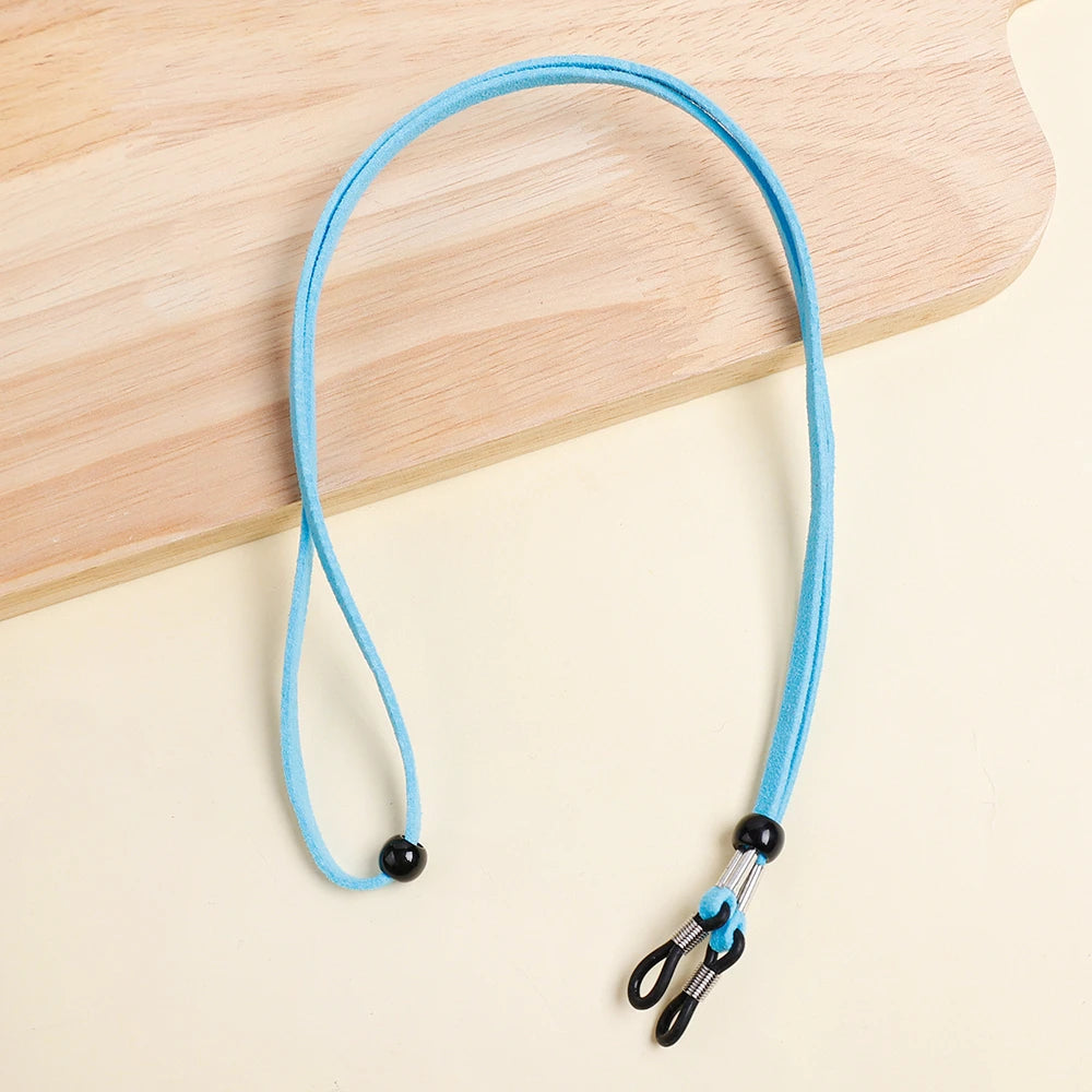 A bright blue adjustable lanyard for glasses is displayed on a light wooden surface.