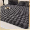 A gray quilted fabric blanket or comforter is shown on a bed, featuring implanted electrostatic conductivity wire.