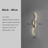 A black aluminum and silicone LED wall lamp with a curved design mounted on a gray wall.