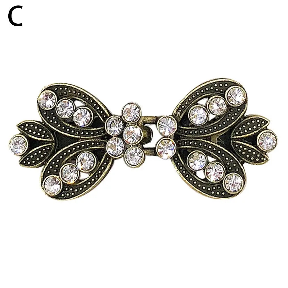 Vintage gold-toned swirl clip featuring clear rhinestones used to fasten sweaters and shawls